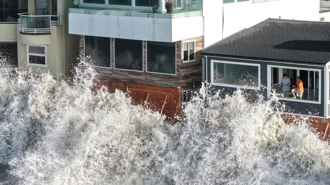 LONG BEACH, CALIFORNIA - OCTOBER 09: In an aerial view, people watch from a home as a Pacific Ocean wave crashes into a seawall amid powerful surf on October 9, 2026 in Long Beach, California.