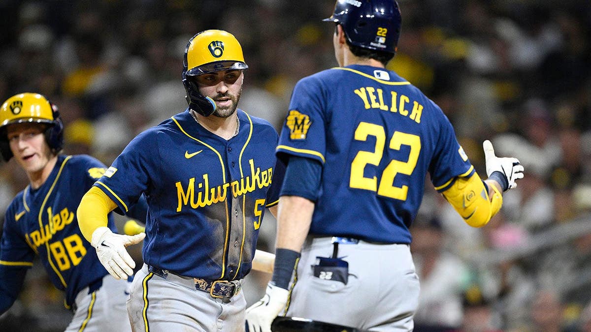 Garrett Mitchell is congratulated by Christian Yelich after scoring a run for the Milwaukee Brewers.