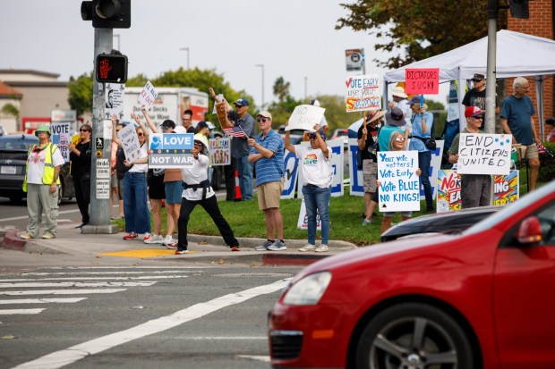 San Diego, California - People hold up signs during a No Kings Rally at the intersection of Camino Ruiz and Mira Mesa Boulevard in Mira Mesa on Saturday, Oct. 17, 2026. With the general election just around the corner, demonstrators encouraged early voting during the rally. (Kristian Carreon / The San Diego Union-Tribune)