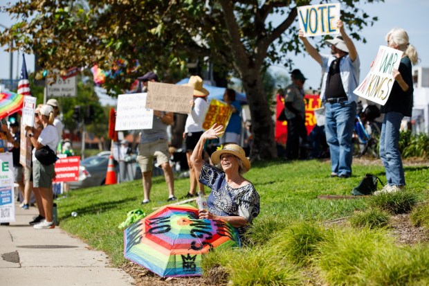 San Diego, California - Mary Brown, 73, of Clairemont, waves to passing motorists during a No Kings Rally at the intersection of Camino Ruiz and Mira Mesa Boulevard in Mira Mesa on Saturday, Oct. 17, 2026. With the general election just around the corner, demonstrators encouraged early voting during the rally. (Kristian Carreon / The San Diego Union-Tribune)