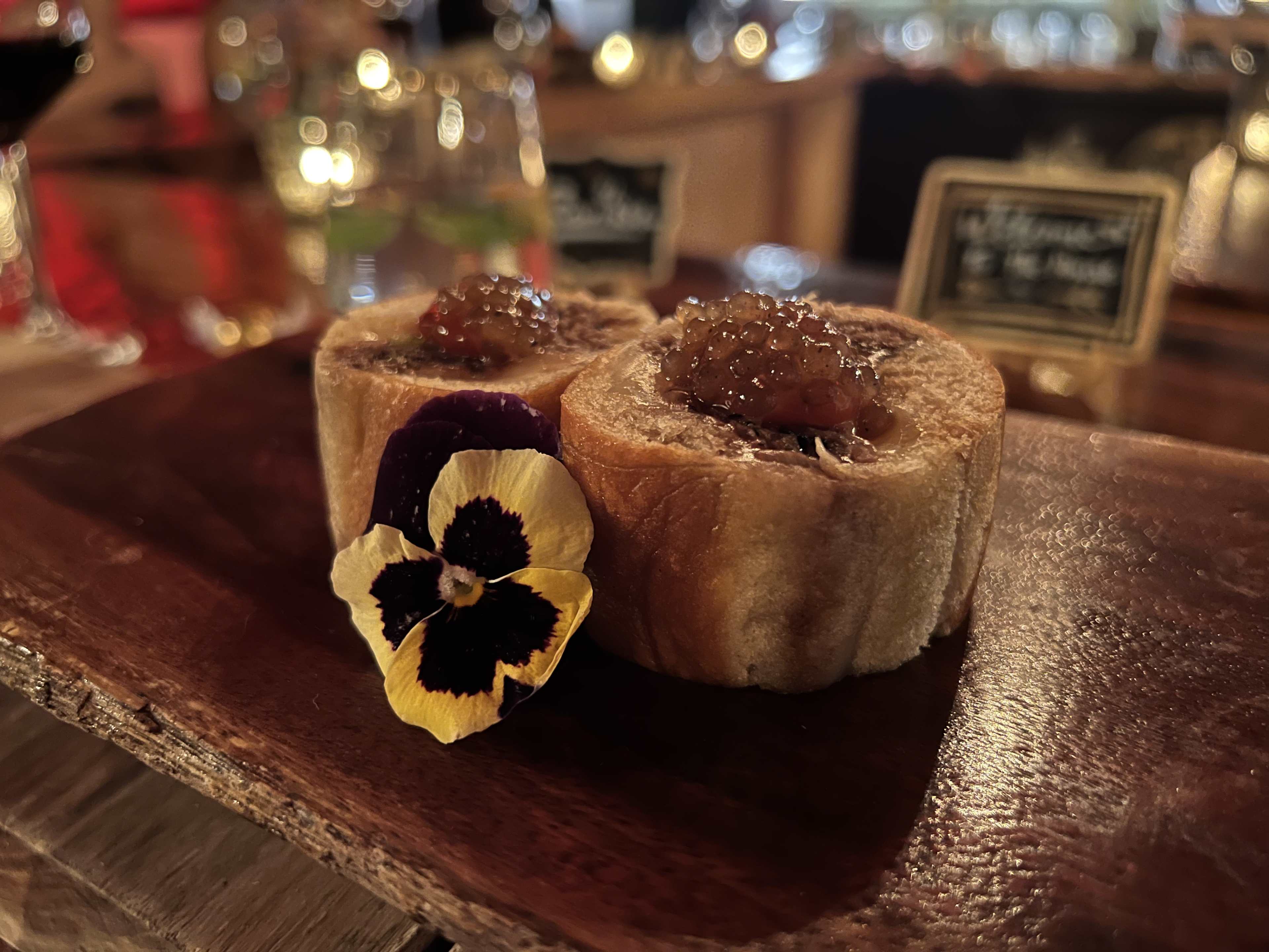 Philly cheesesteak topped with truffle-infused pearls and garnished with a yellow flower.
