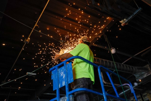 A worker installs AC ductwork in the underground garage fitness...