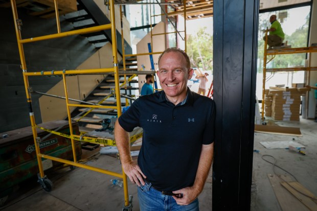 Daniel Kennerly stands in the foyer of the home as crew members work in the area that will feature a glass-enclosed library and conference room. The 15,176-square-foot estate is being built by Alair Homes Orlando and will be the centerpiece showcase home for the 2026 International Builders' Show. (Rich Pope/Orlando Sentinel)