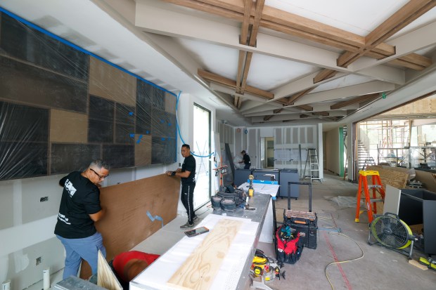 A crew begins placing walnut cabinets in the kitchen and...