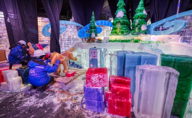 Chinese artisans carve an elf and a dog during a...