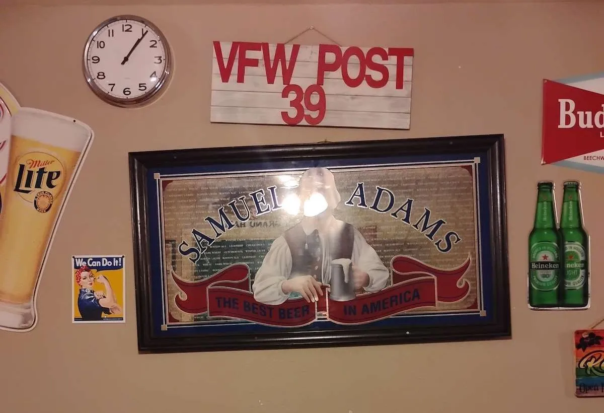 a wall with beer decor, a mirror, a clock, and a sign that reads "VFW Post 39"