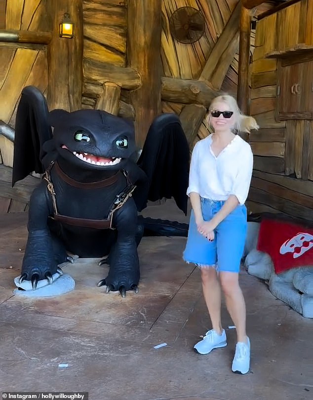 Holly looked stylish as she tucked a white shirt into a pair of long blue denim shorts and kept comfortable in a pair of white trainers as she posed with How To Train Your Dragon's Toothless