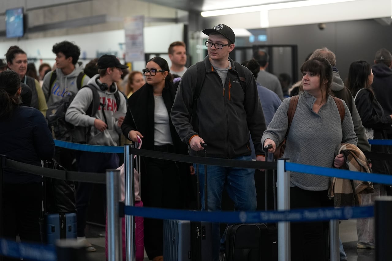 Travelers move through a security line at an airport. 