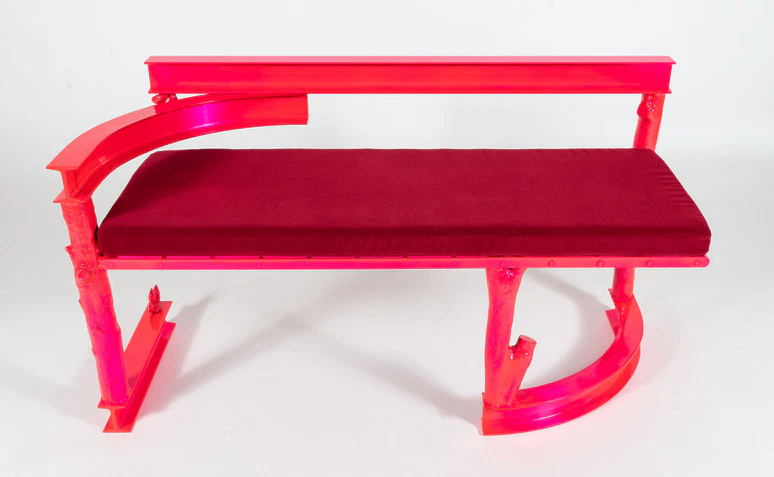 Bright pink and red modern bench with curved armrests and a padded seat on a white background.