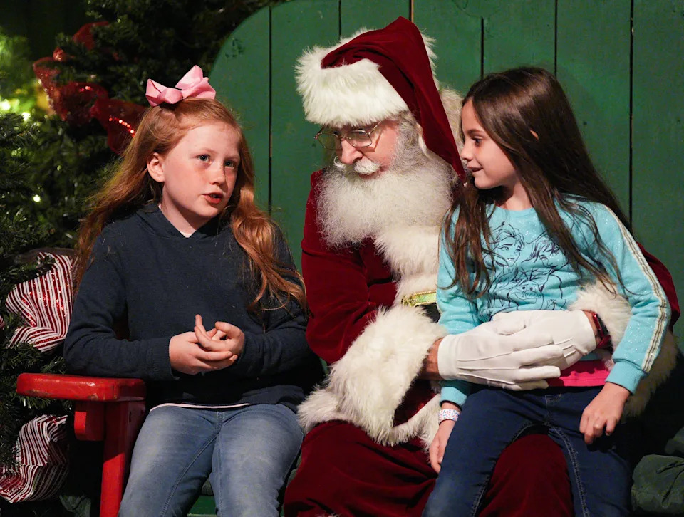Coraline Word, 8, left, tells Santa what she wants for Christmas as Santa holds her sister, Kinsley Word, 6, during the Colors of the Wild event at the Jacksonville Zoo on Sunday, November 23, 2025.