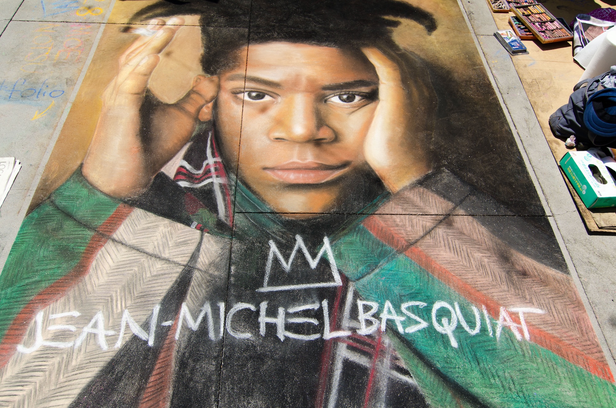 photo of a sidewalk mural depicting a photorealistic chalk drawing of the artist Jean-Michel Basquiat