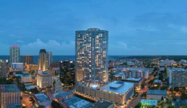 A nighttime aerial view of downtown St. Petersburg with the 400 Central tower lit up at the center of the skyline.
