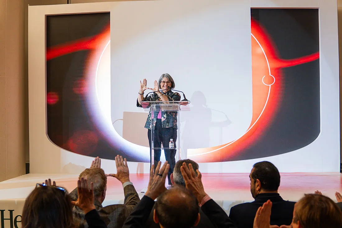 Daniella Cava Levine making the U hand sign onstage at the UHealth SoLé Mia VIP event