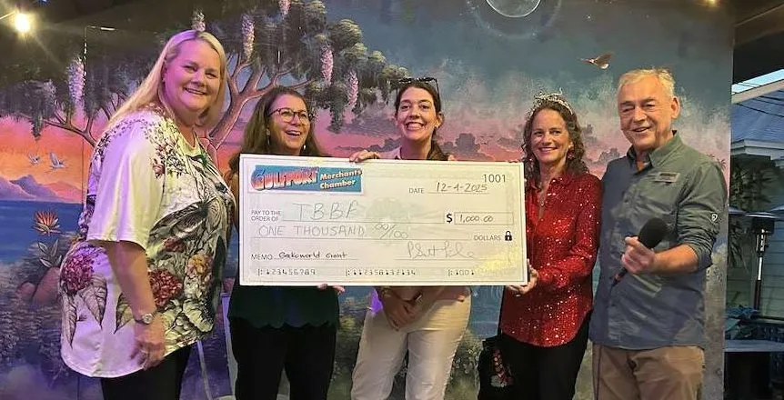 5 people standing on stage holding a giant check. 