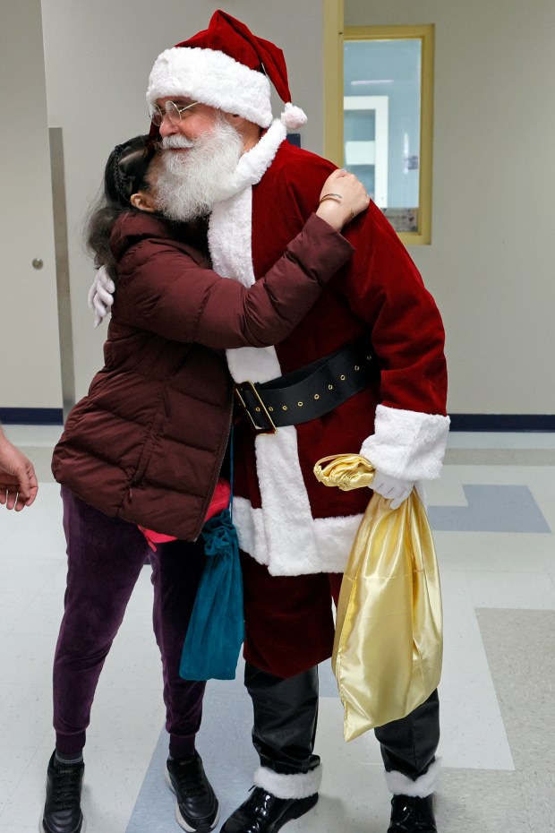 Sun Sentinel staff writer Ben Crandell, dressed as Santa Claus, gets a hug from senior Maria Jose Alcocer before leaving Fort Lauderdale High School on Monday, Dec. 15, 2025. Homeroom classes at St. Anthony Catholic School "adopted" students with special needs and donated holiday gifts delivered by Santa. (Amy Beth Bennett / South Florida Sun Sentinel)