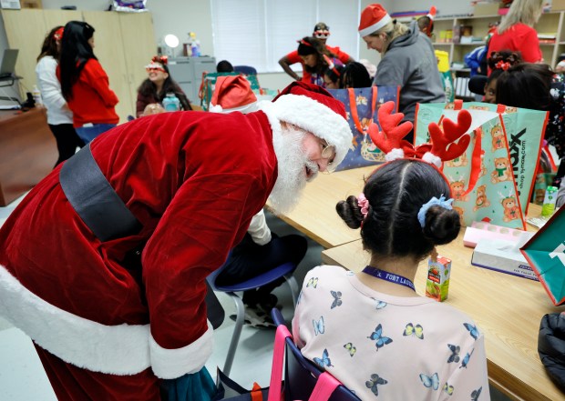 Sun Sentinel staff writer Ben Crandell, dressed as Santa Claus, talks with junior Sophie Ramirez at Fort Lauderdale High School on Monday, Dec. 15, 2025. Homeroom classes at St. Anthony Catholic School "adopted" students with special needs and donated holiday gifts delivered by Santa. (Amy Beth Bennett / South Florida Sun Sentinel)