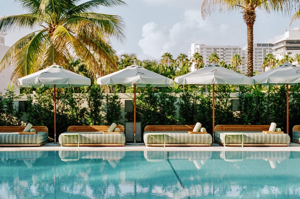 Outdoor lounge area with sunbeds and umbrellas by a pool