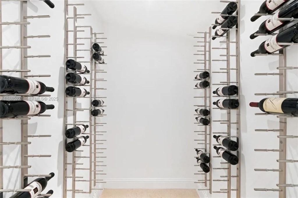a spacious wine room is shown with sparsely supplied racks on two walls