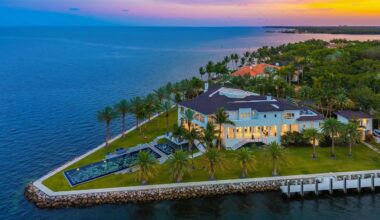 a massive mansion sits on an estate surrounded by blue water