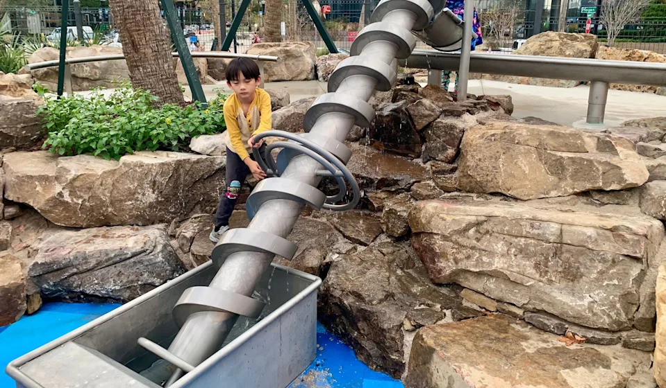 Wlliam Lu, 5, spins one of the interactive exhibits in the splash pad at Riverfront Plaza on the park's official opening day of Dec. 5, 2025.