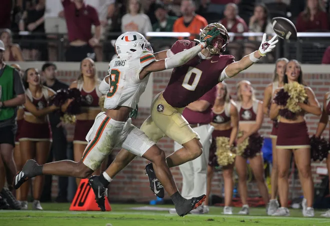 Oct 4, 2025; Tallahassee, Florida, USA; Florida State Seminoles wide receiver Duce Robinson reaches for a pass against Miami Hurricanes defensive back Jakobe Thomas (8) during the second half at Doak S. Campbell Stadium. Mandatory Credit: Melina Myers-Imagn Images