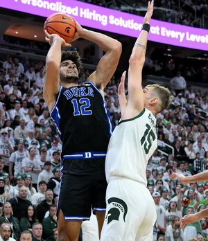 Dec 6, 2025; East Lansing, Michigan, USA; Duke Blue Devils forward Cameron Boozer (12) shoots past Michigan State Spartans center Carson Cooper (15) during the first half at Jack Breslin Student Events Center. Mandatory Credit: Dale Young-Imagn Images