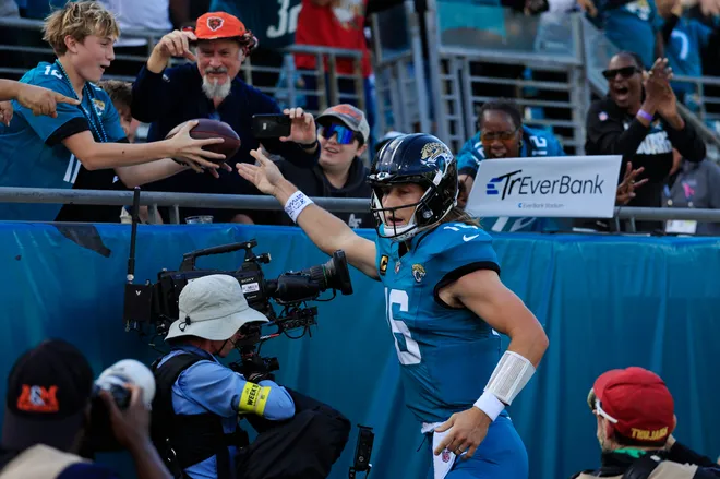 Jacksonville Jaguars quarterback Trevor Lawrence (16) hands the ball to a fan after scoring a rushing touchdown during the first quarter of an NFL football matchup at EverBank Stadium, Sunday, Dec. 14, 2025, in Jacksonville, Fla. [Corey Perrine/Florida Times-Union]