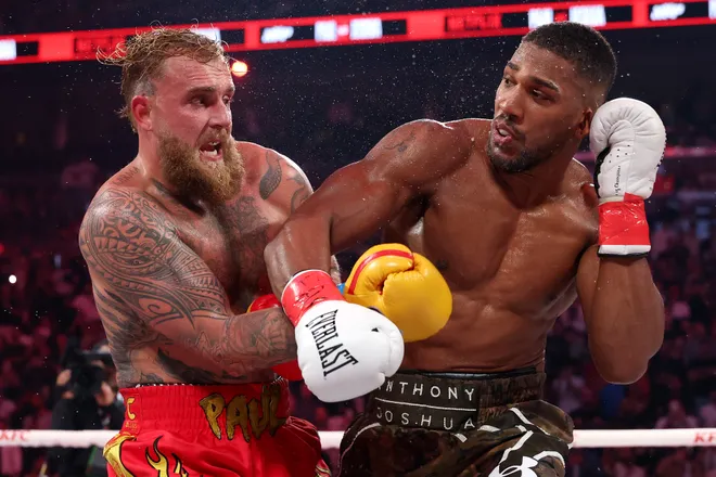 MIAMI, FLORIDA - DECEMBER 19: (L-R) Jake Paul fights Anthony Joshua in their heavyweight bout during Jake Paul v Anthony Joshua at Kaseya Center on December 19, 2025 in Miami, Florida. (Photo by Ed Mulholland/Getty Images for Netflix)