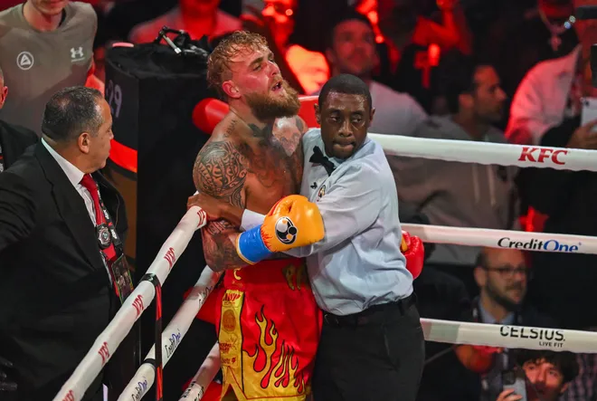 Referee Christopher Young holds US boxer and influencer Jake Paul against the ropes during his fight against British boxer Anthony Joshua (off frame) in a non-title heavyweight bout at the Kaseya Center in Miami, Florida, on December 19, 2025. (Photo by Giorgio VIERA / AFP via Getty Images)