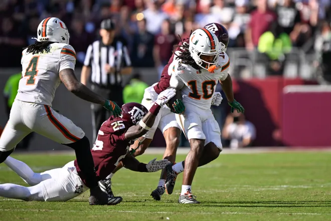 Dec 20, 2025; College Station, TX, USA; Texas A&M Aggies safety Dalton Brooks (25) strips the ball from Miami Hurricanes wide receiver Malachi Toney (10) during the second half of the first round game of the CFP National Playoff at Kyle Field. Mandatory Credit: Jerome Miron-Imagn Images