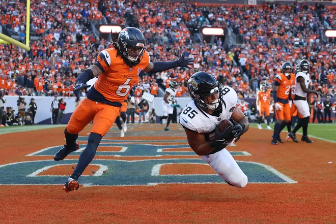 DENVER, COLORADO - DECEMBER 21: Brenton Strange #85 of the Jacksonville Jaguars catches a pass in front of P.J. Locke #6 of the Denver Broncos for a second quarter touchdown at Empower Field At Mile High on December 21, 2025 in Denver, Colorado. (Photo by Matthew Stockman/Getty Images)