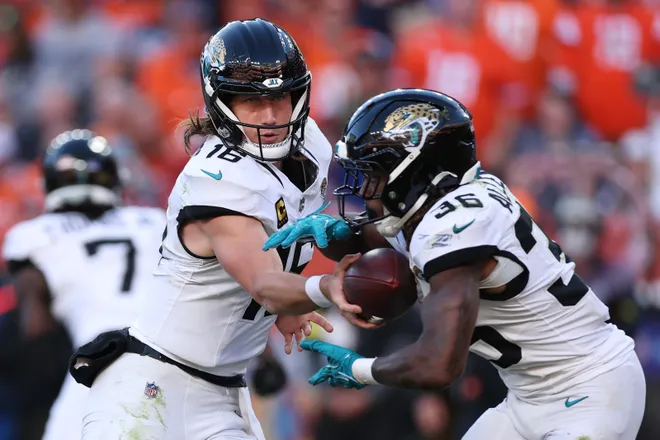 DENVER, COLORADO - DECEMBER 21: Trevor Lawrence #16 hands off to Lequint Allen Jr. #36 of the Jacksonville Jaguars during the second quarter against the Denver Broncos at Empower Field At Mile High on December 21, 2025 in Denver, Colorado. (Photo by Matthew Stockman/Getty Images)