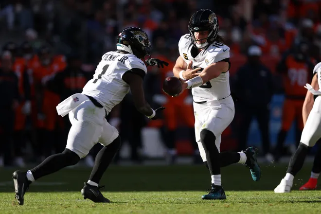 DENVER, COLORADO - DECEMBER 21: Trevor Lawrence #16 hands off to Travis Etienne Jr. #1 of the Jacksonville Jaguars during the first quarter against the Denver Broncos at Empower Field At Mile High on December 21, 2025 in Denver, Colorado. (Photo by Matthew Stockman/Getty Images)
