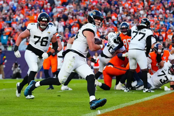Dec 21, 2025; Denver, Colorado, USA; Jacksonville Jaguars quarterback Trevor Lawrence (16) rushes for a touchdown against the Denver Broncos during the second half at Empower Field at Mile High. Mandatory Credit: Ron Chenoy-Imagn Images