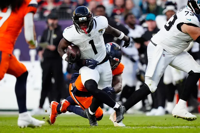 Dec 21, 2025; Denver, Colorado, USA; Jacksonville Jaguars running back Travis Etienne (1) rushes the ball against the Denver Broncos during the second half at Empower Field at Mile High. Mandatory Credit: Ron Chenoy-Imagn Images