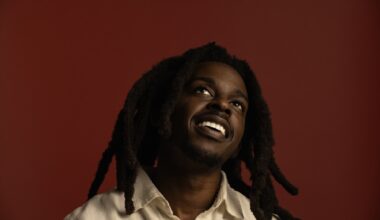 Photo of a man with dreadlocks smiling and looking up.