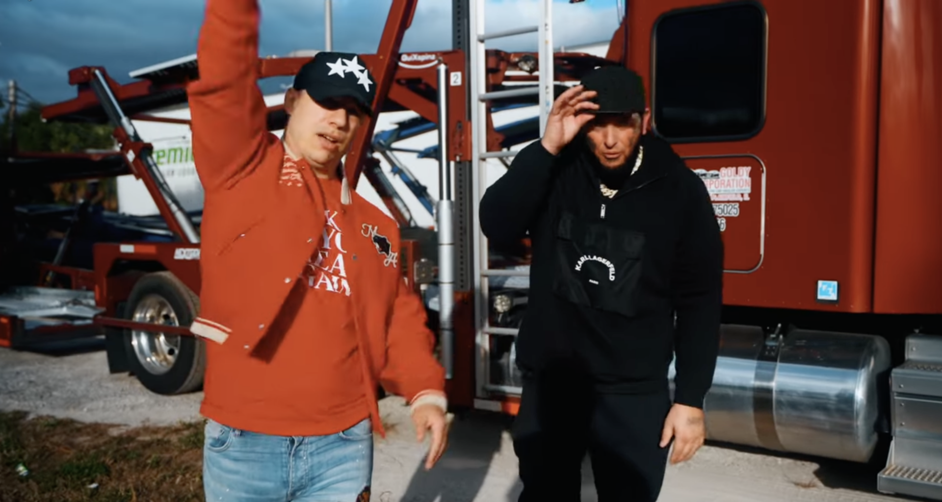 Photo of two men singing next to a truck.