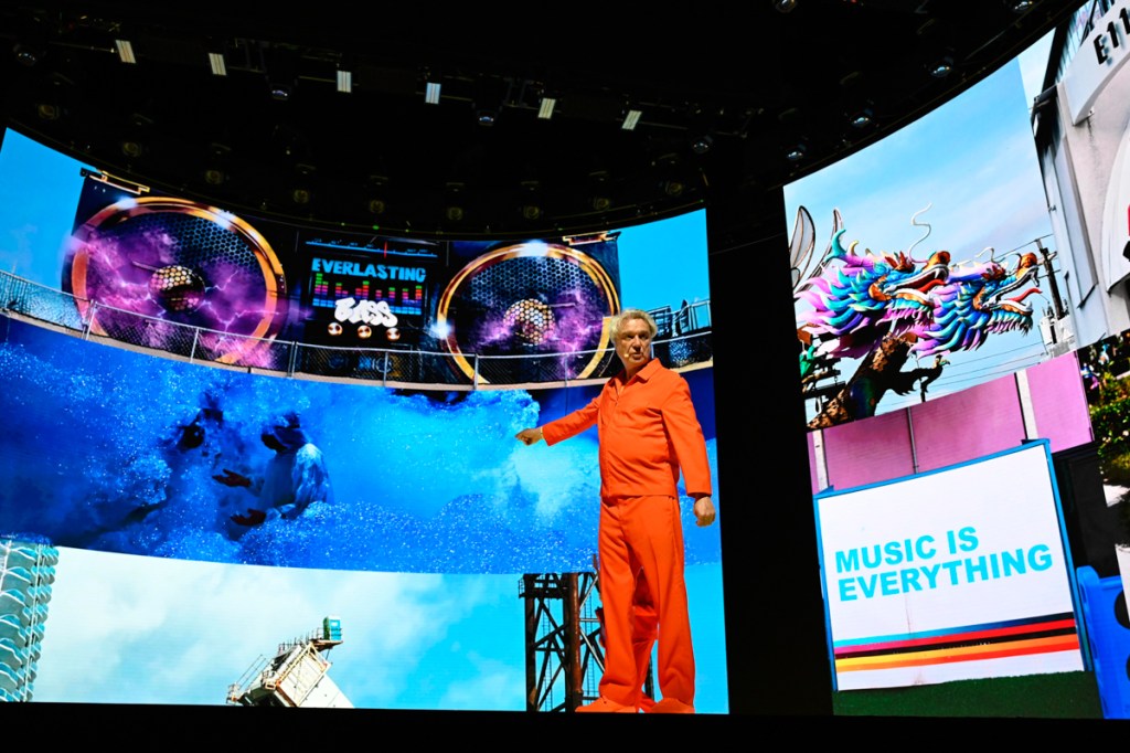 A man on stage pointing at an LED screen.  