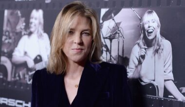 Photo of a blonde woman looking at the camera wearing a black suit.