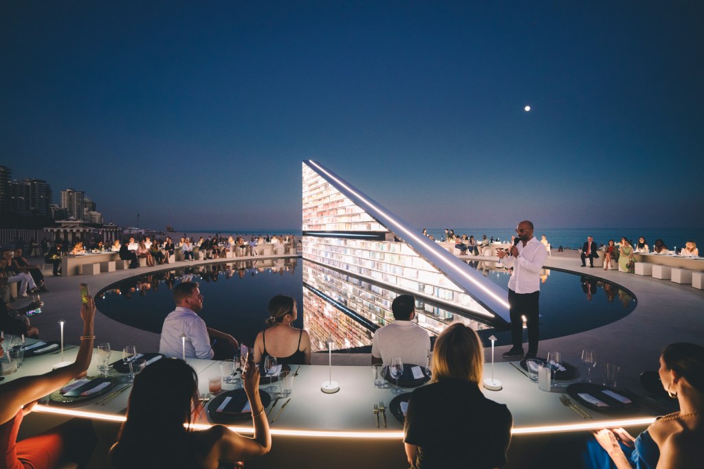 Sam Palmer speaking in front of Es Devlin's "Library of Us" sculpture at the Faena Art Week Edible Library dinner.