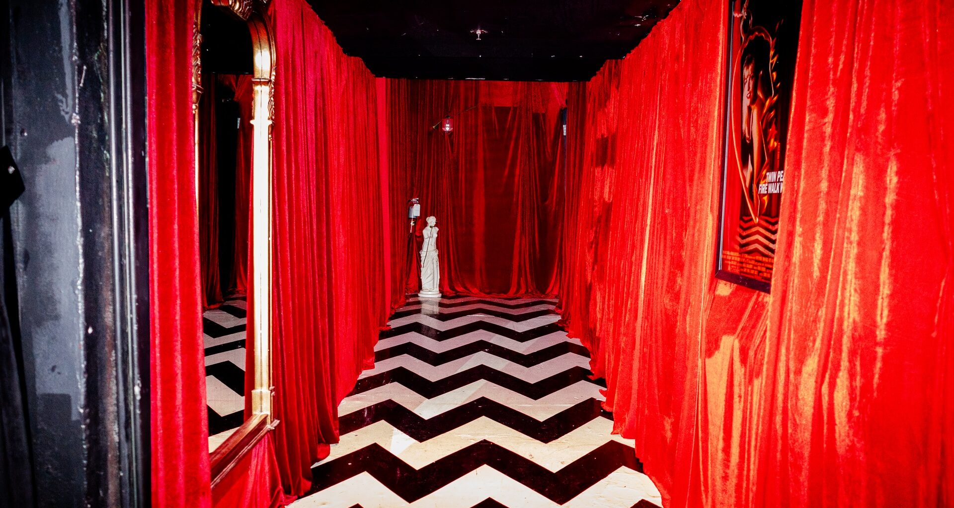 A photo pf a room with a corridor with black and white floors and red walls.