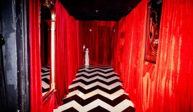 A photo pf a room with a corridor with black and white floors and red walls.