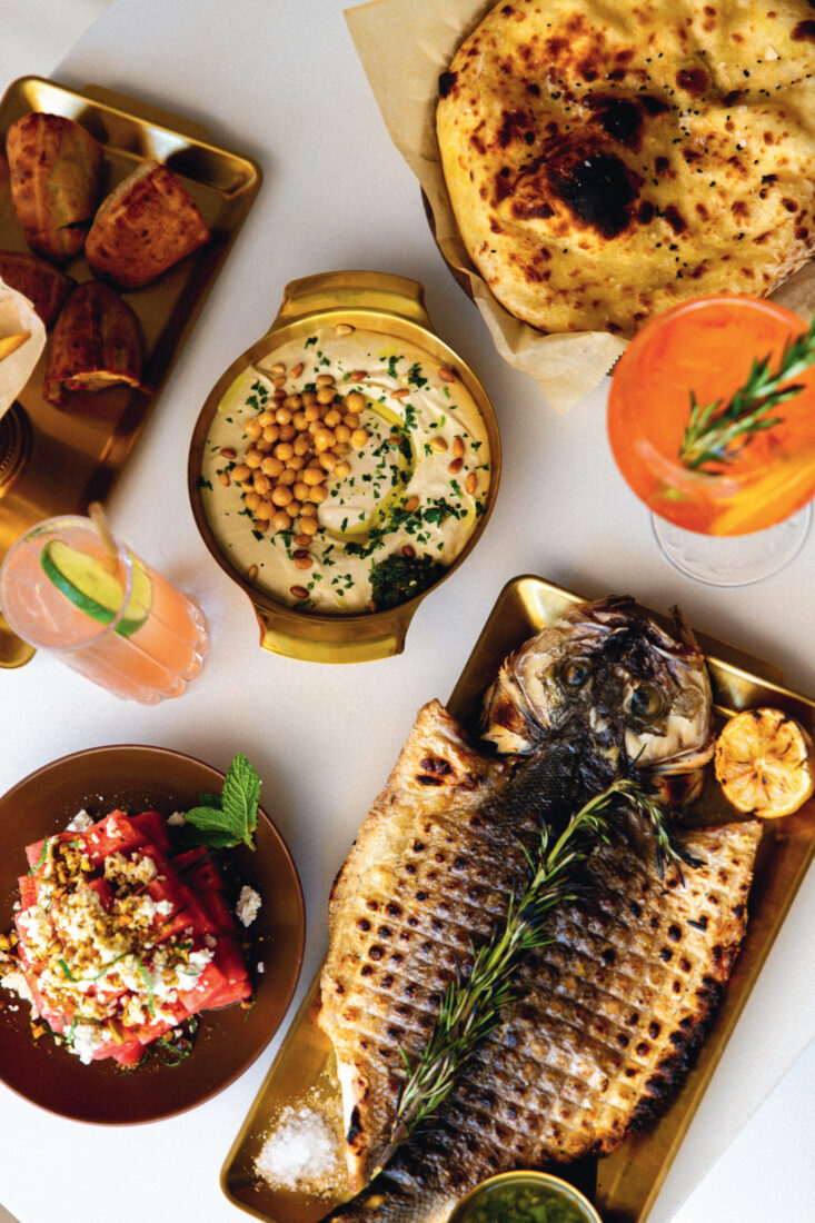 A branzino entree, arayes burger, summer salad, and hummus.