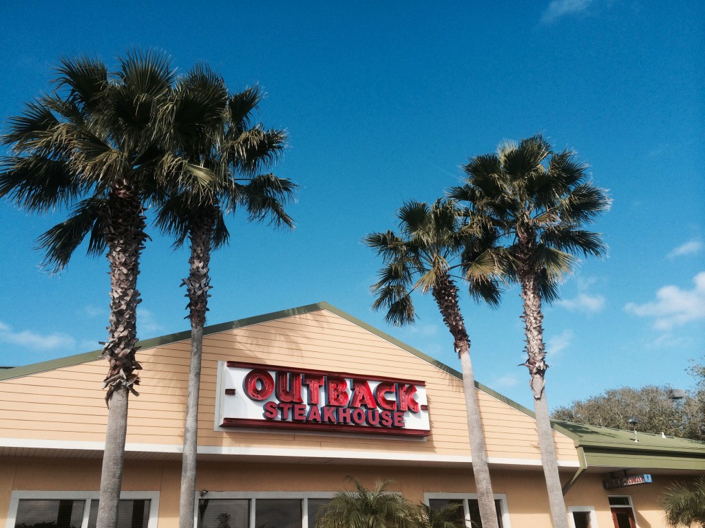 Outback Steakhouse restaurant with palm trees.