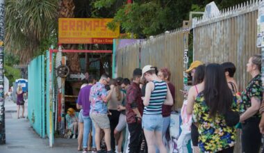 Photo of people in line to enter a bar. A painted wooden sign at the venue reads, "Gramps"