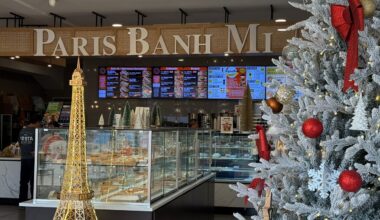 a white Christmas tree with red ornaments is situated in front of an Eiffel Tower statue at the Paris Banh Mi Bakery in Orlando.