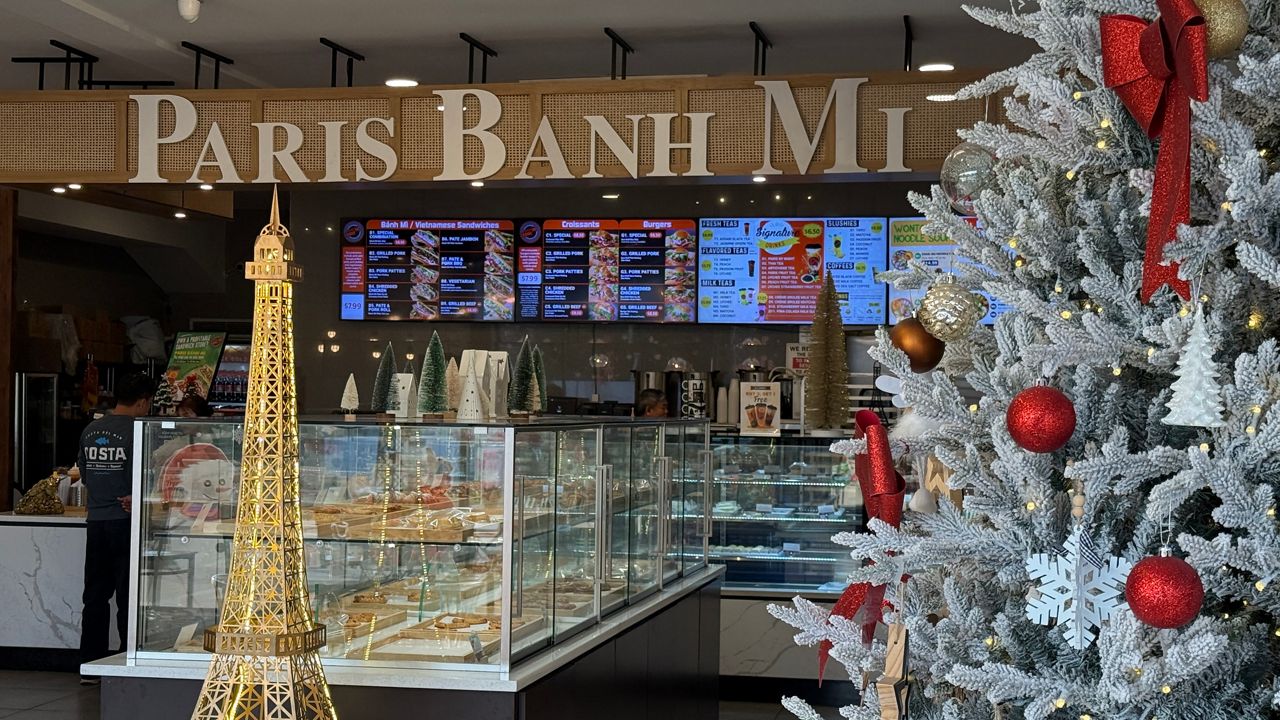 a white Christmas tree with red ornaments is situated in front of an Eiffel Tower statue at the Paris Banh Mi Bakery in Orlando.