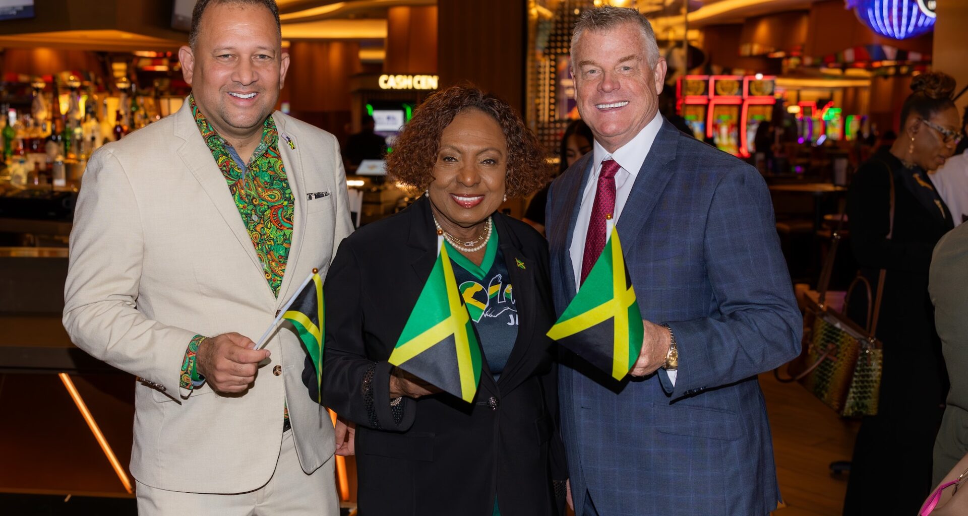 A group of three people holding Jamaican flags