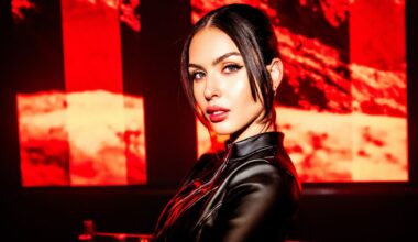 Photo of a woman wearing black against a red LED screen