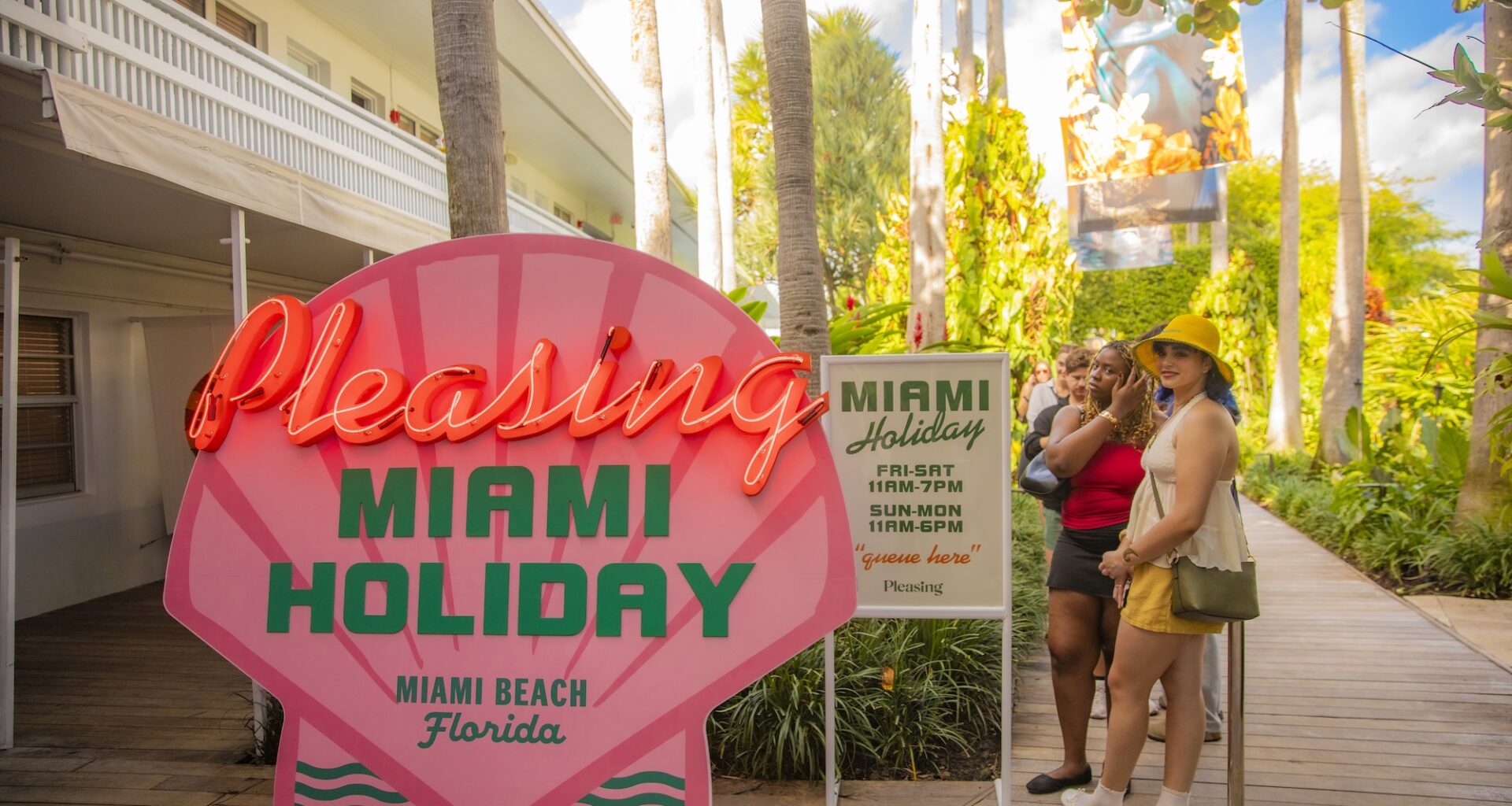 photo of a wooden sign of a sign painted like a pink seashell reading "Pleasing Miami Holiday, Miami Beach Florida"